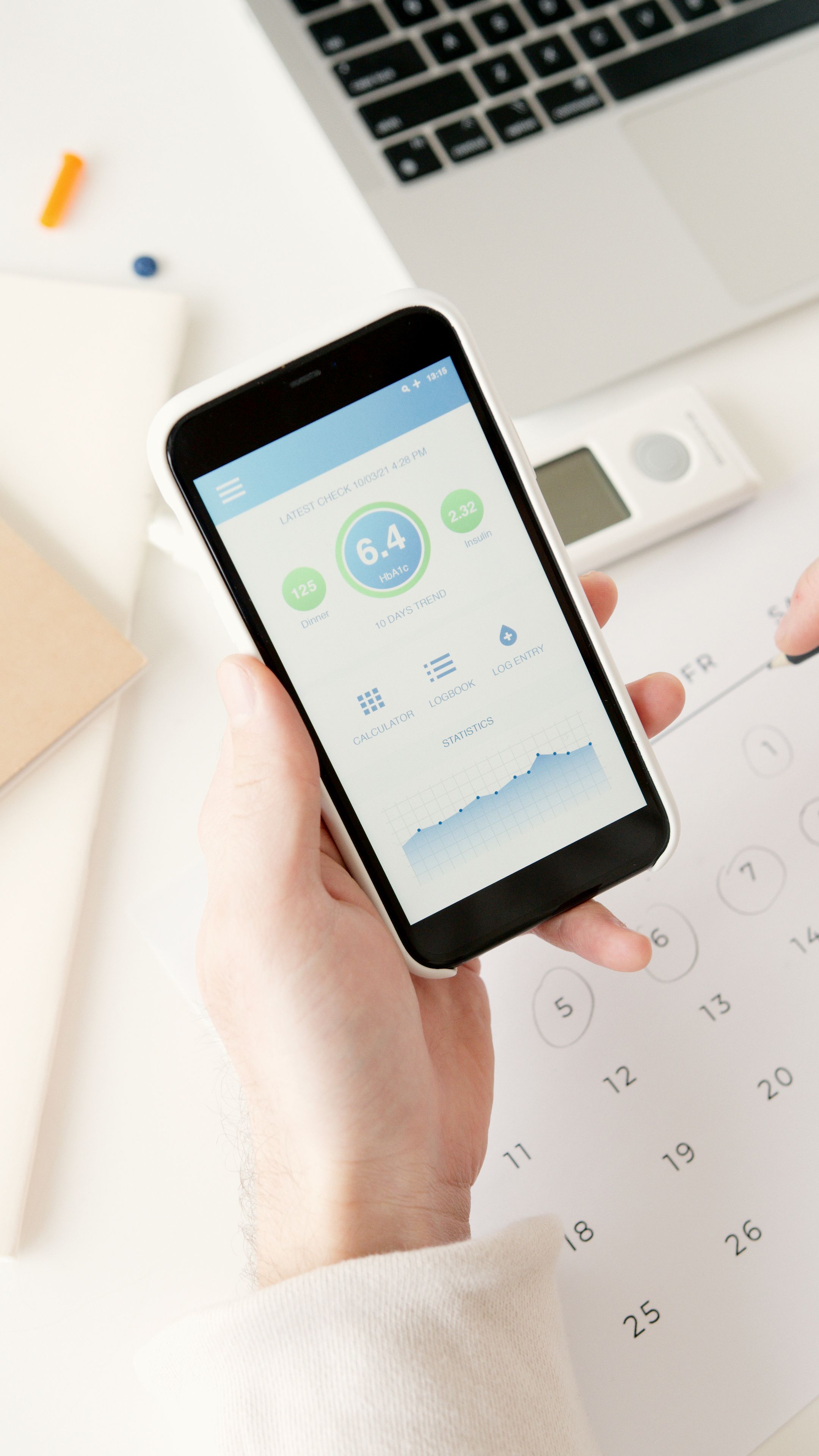 Celular con aplicacion de salud sobre calendario y escritorio